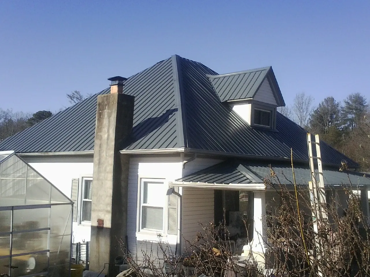 Dark blue standing seam metal roof on a white farmhouse with dormer — Slate & Tile Roof Repair by Roofing Brothers in Talladega