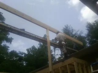 Carpenter setting a ridge beam over a new addition frame — Ice Dam Removal by Roofing Brothers in Talladega