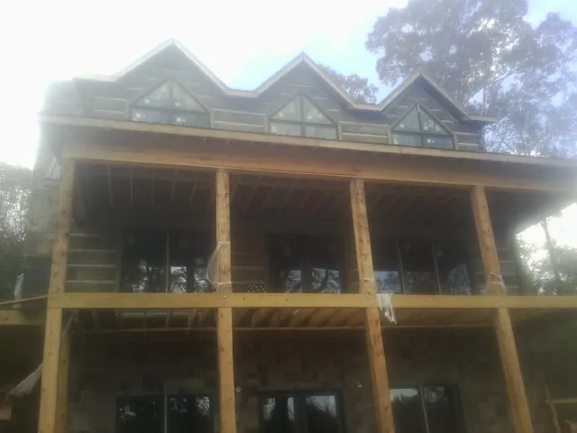 Dormers and porch framing on a large log home under construction — Roof Coating work by our crew in Talladega