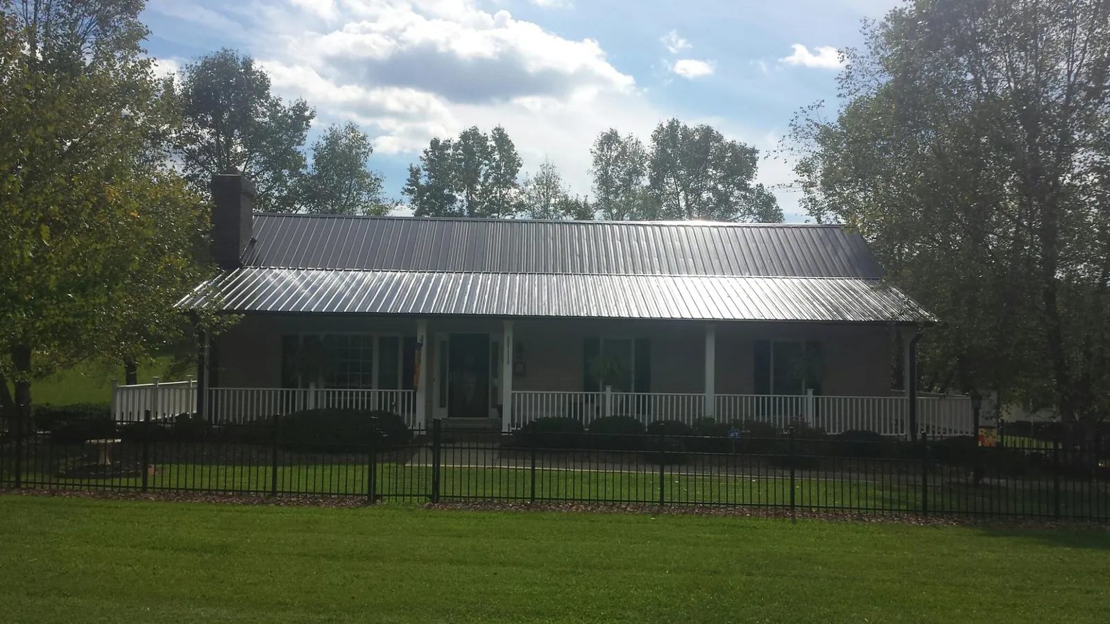 Gray metal roof on a brick ranch with a full width front porch — Gutter Guard Installation work by our crew in Talladega